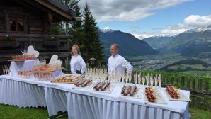 A table set up outdoors with various food items and a scenic mountain view in the background.
