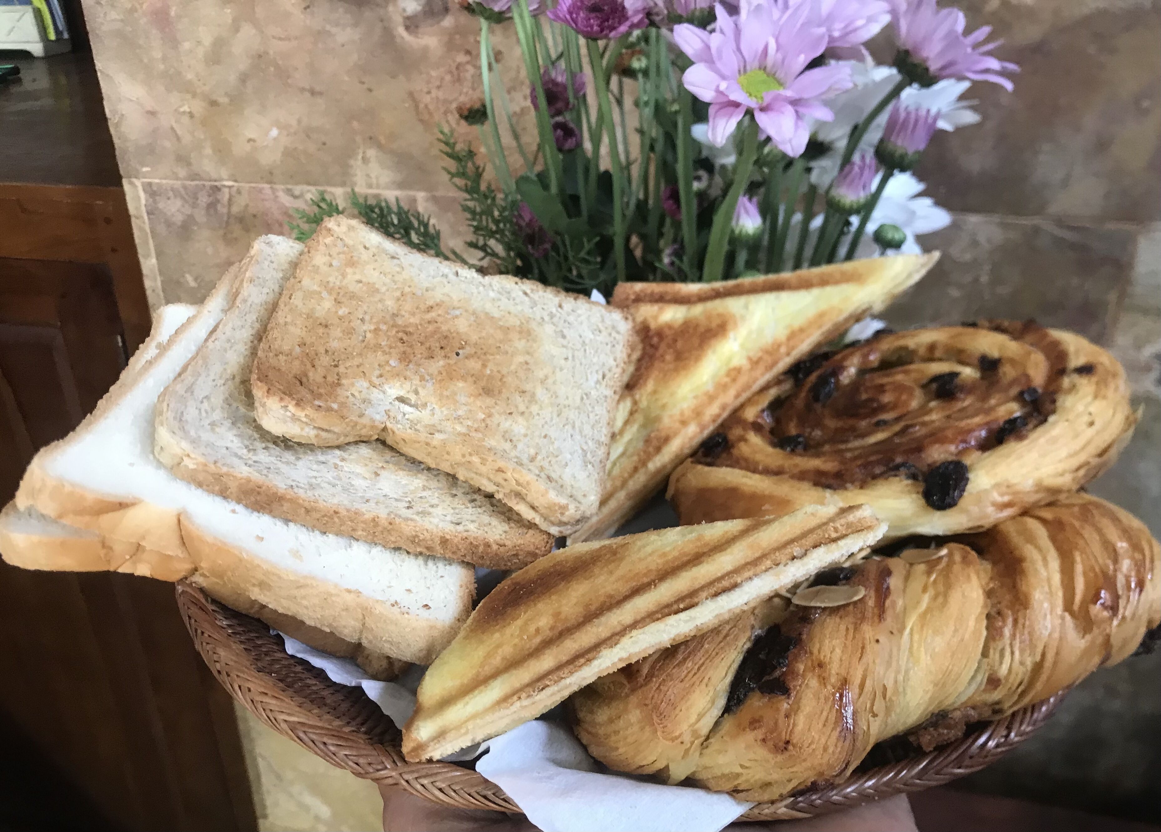 Ein Korb mit verschiedenen Brotsorten, darunter Weißbrot und ein Zimtschnecke.