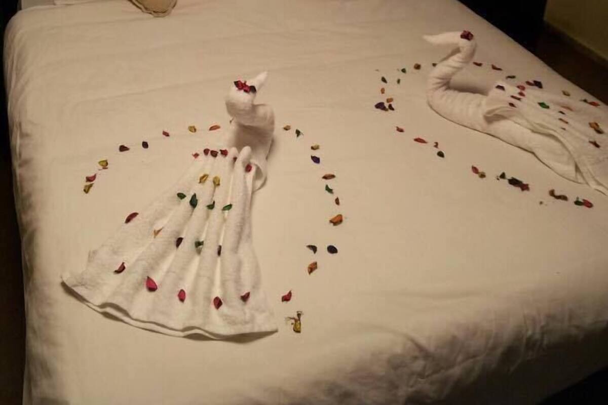 A hotel room with a large bed, two pillows, and a headboard.