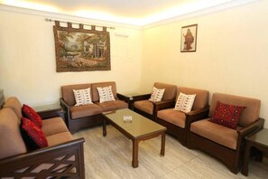 A living room with a sofa set, a coffee table, and two wall-mounted paintings.