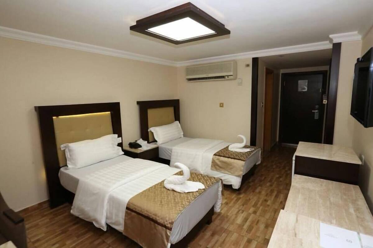 A hotel room with two beds, a desk, and a TV.