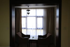 Un comedor con mesa y sillas, un lámpara colgante y una ventana con cortinas.