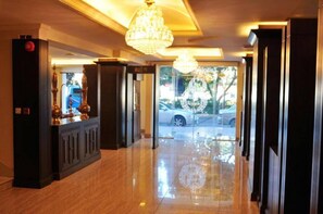 A hotel lobby with a polished floor, a reception desk with a chandelier, and a view of the outside. - Zaitouna Hotel (Aqaba)