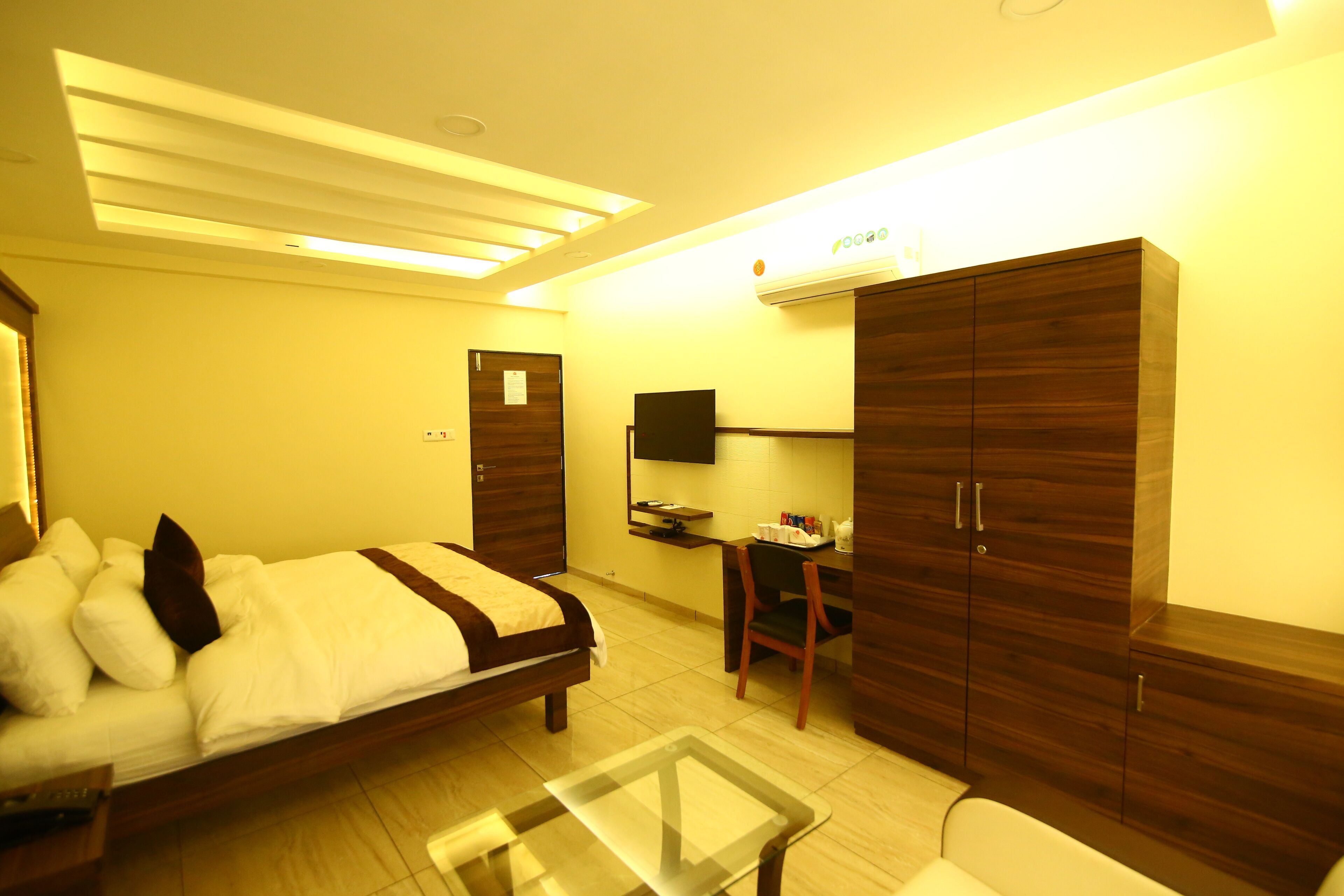 A hotel room with a bed, a desk, a chair, a TV, and wardrobes.