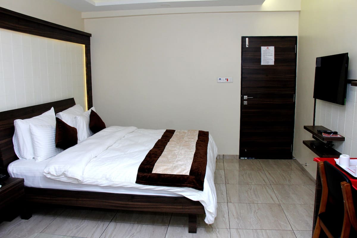 Una camera d'albergo con un letto, una scrivania con una sedia, una televisione e una porta.