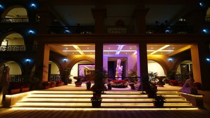 A hotel lobby with a grand staircase, multiple arches, and a central decorative pillar. - GD Hotel (Navsari)