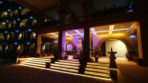 A hotel entrance with a grand staircase, multiple balconies, and decorative lighting. - GD Hotel (Navsari)