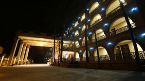 A multi-story hotel with a central courtyard, featuring arched balconies and a covered entrance area. - GD Hotel (Navsari)