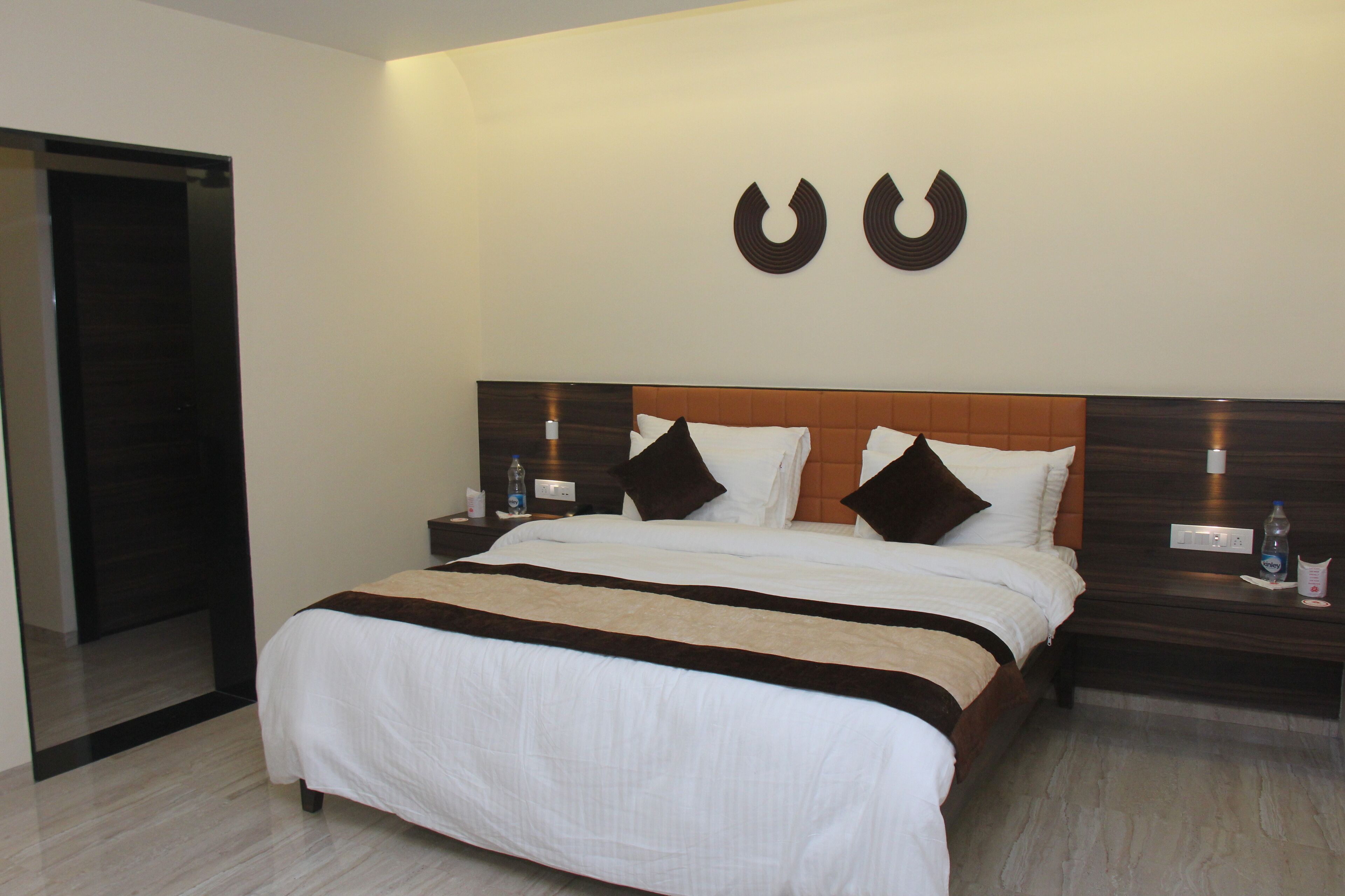 A hotel room with a large bed, two bedside tables, and a wall-mounted light fixture.