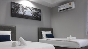 A hotel room with two beds, a painting on the wall, and an air conditioning unit. - Golden Teak Ville (Buriram)