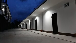 A hotel corridor with multiple rooms, each with a door and a small window. - Golden Teak Ville (Buriram)