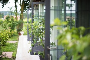 A pathway leading to a modern building with glass walls, surrounded by greenery and potted plants. - Villa Franca in Franciacorta (Passirano)