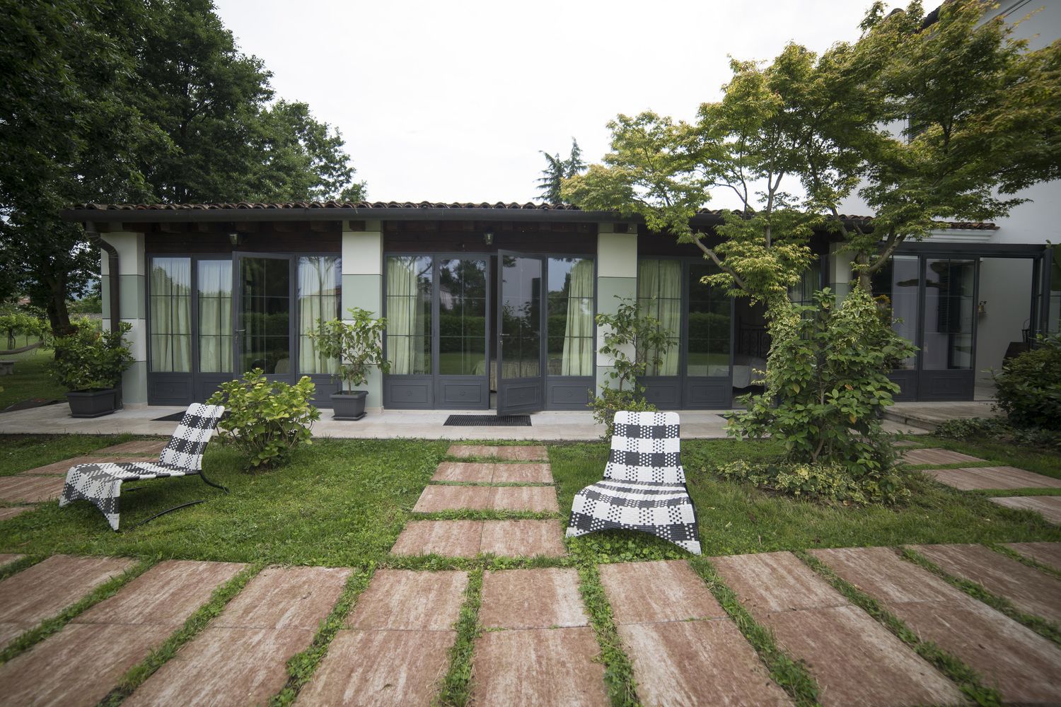 Een modern huis met een patio, compleet met twee lounge stoelen en potplanten.
