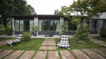 Een modern huis met een patio, compleet met twee lounge stoelen en potplanten.