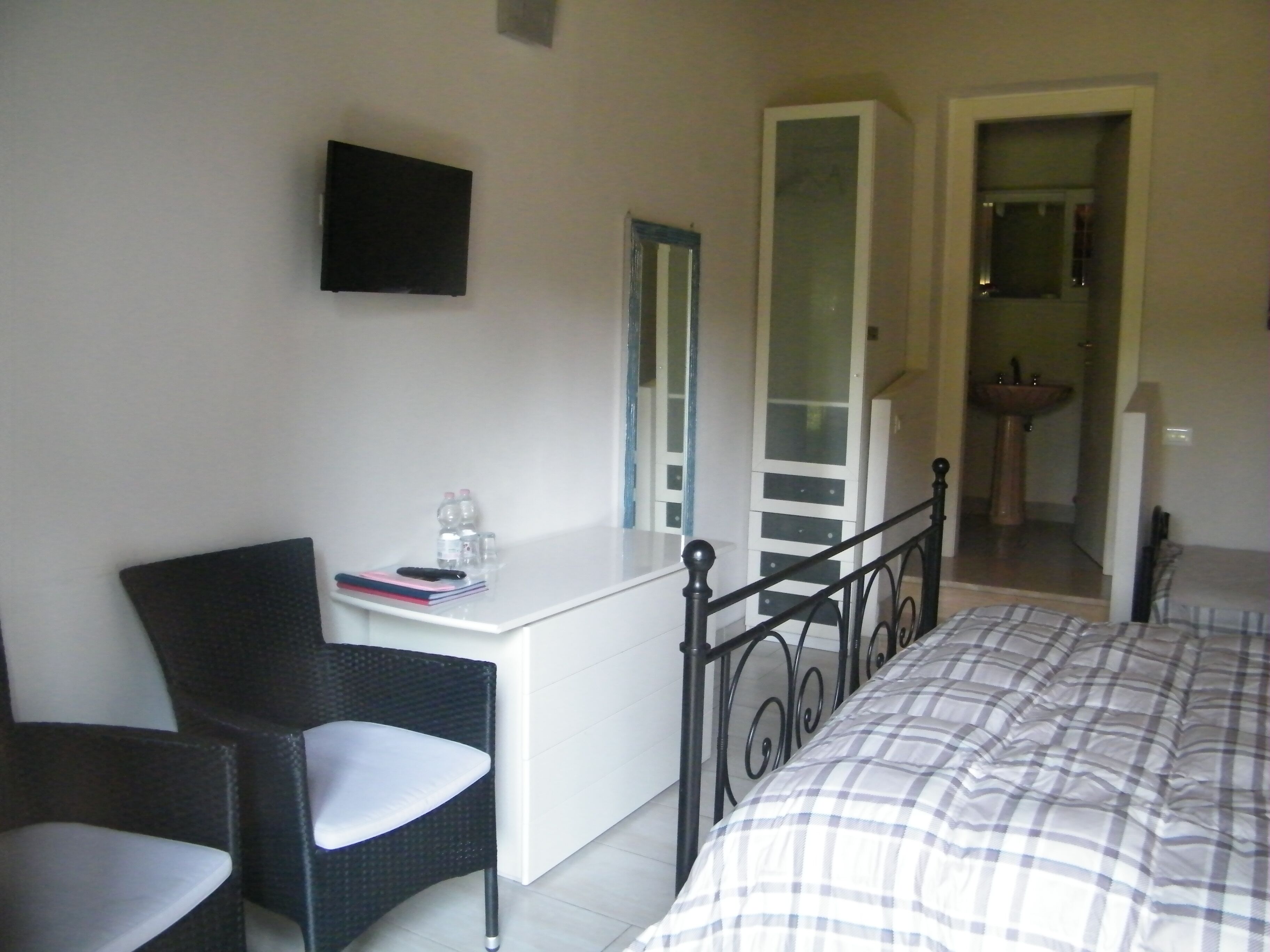A bedroom with a bed, a desk, a chair, a wardrobe, and a bathroom visible through an open door.