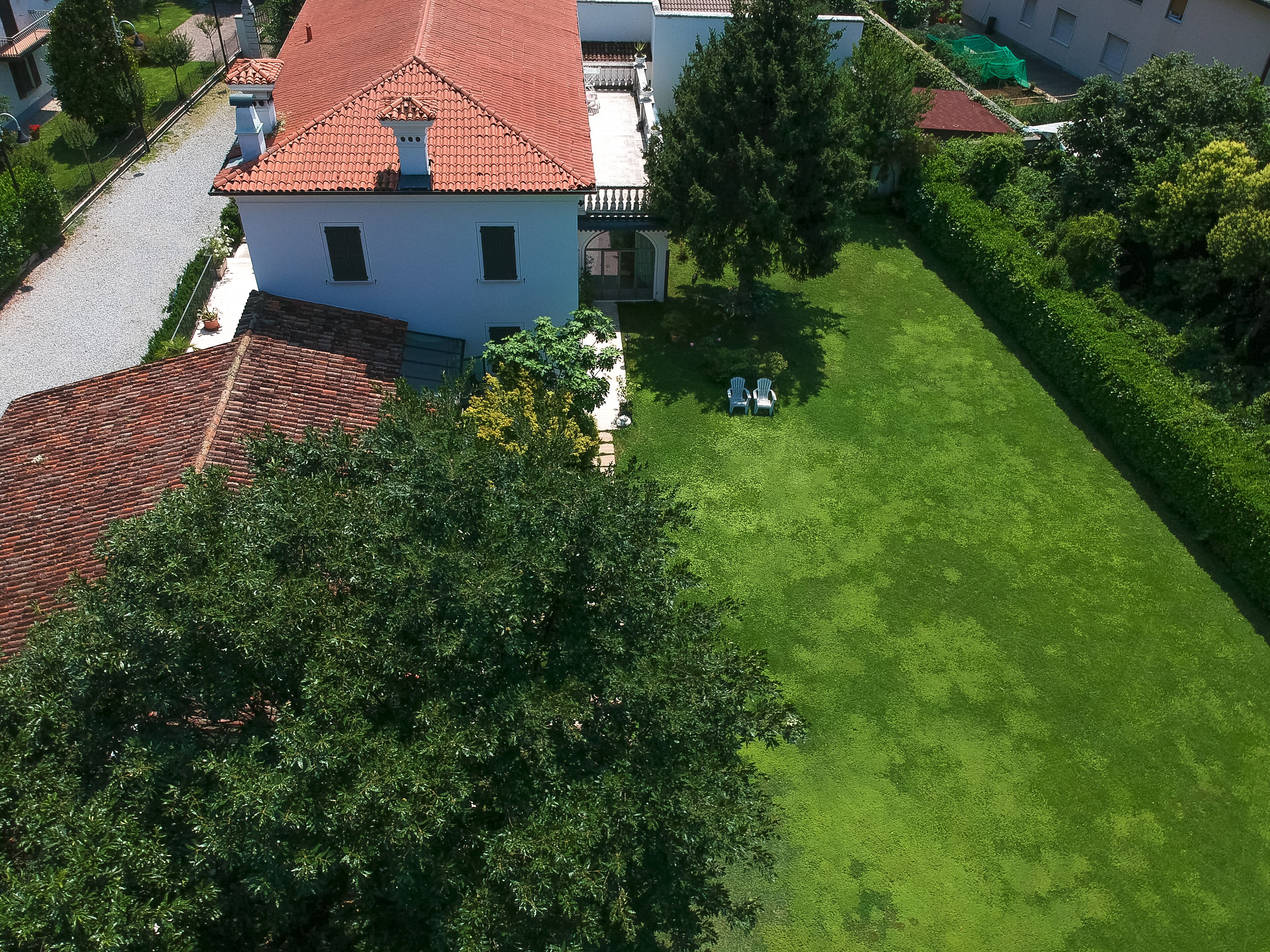 Ein Luftbild eines Hauses mit rotem Ziegeldach, einem gepflegten Rasen und zwei Adirondack-Stühlen.
