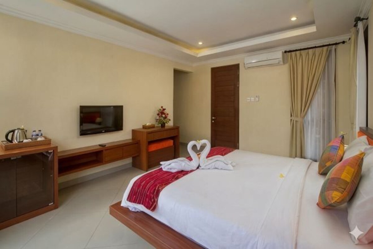 A hotel room with a bed, a TV, a desk, and a wardrobe.