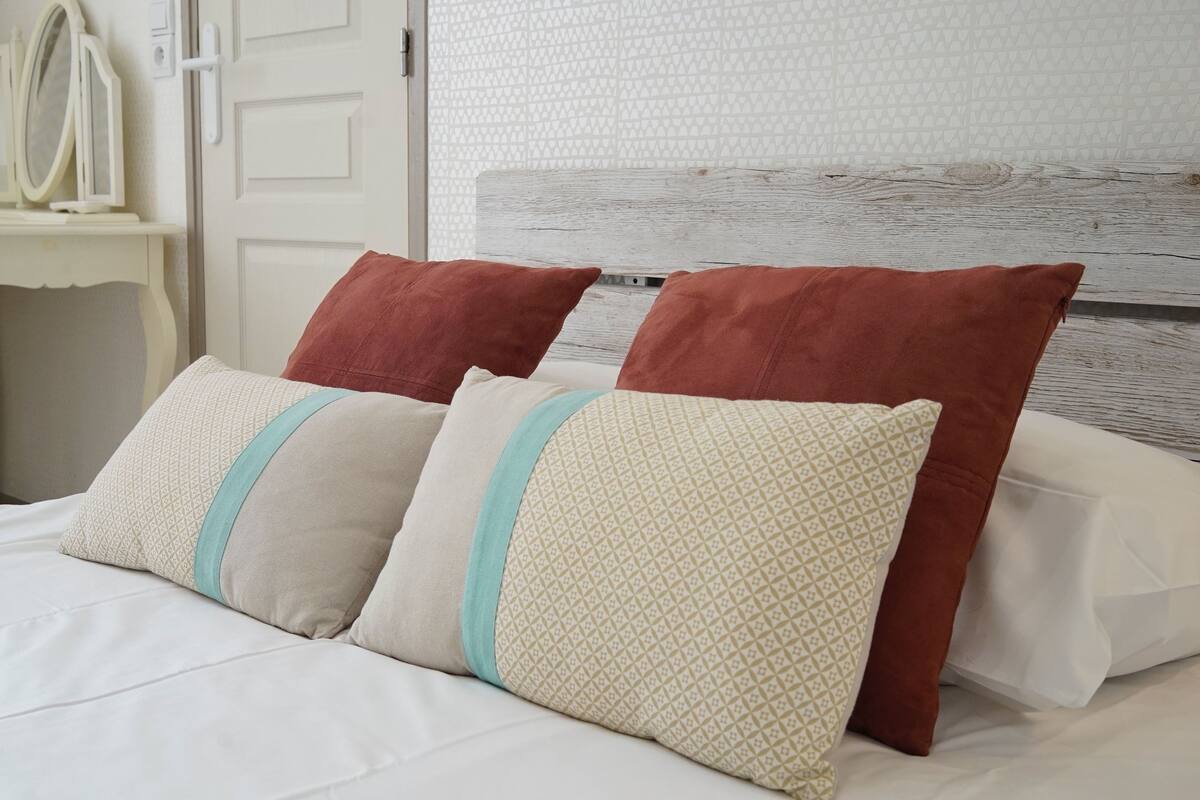 A neatly made bed with patterned pillows and a wooden headboard.