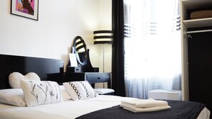 Une chambre d’hôtel comprenant un lit, une table de chevet avec une lampe, un miroir et une armoire.