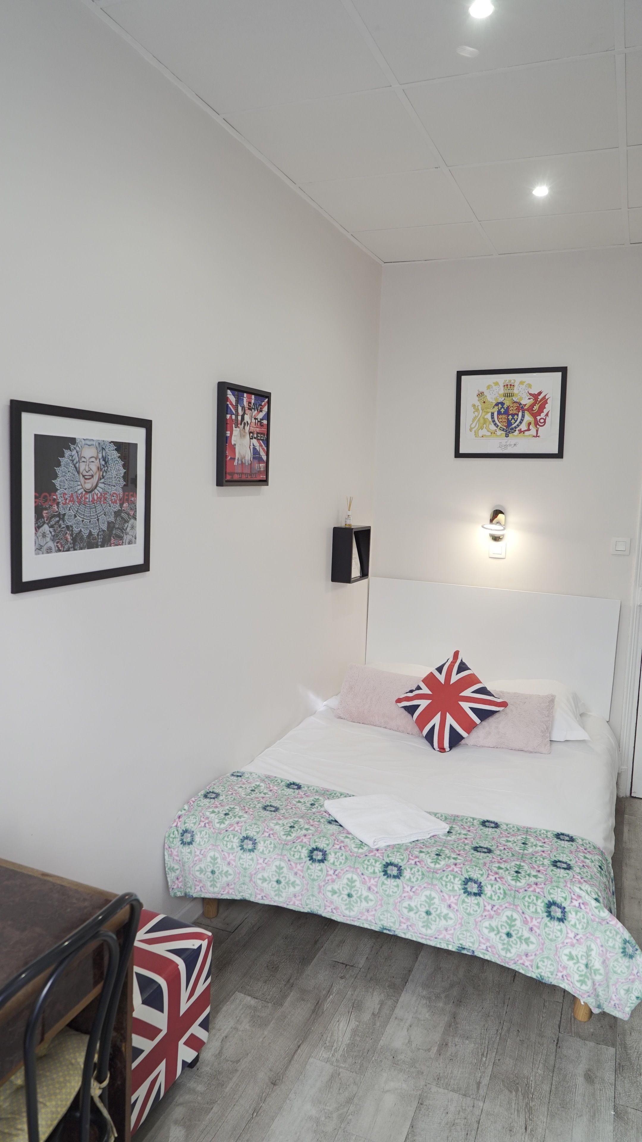 Un dormitorio con cama, escritorio y silla. Hay tres cuadros en la pared.