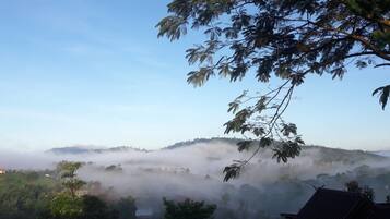 Paisaje montañoso con colinas cubiertas de niebla y cielo despejado.