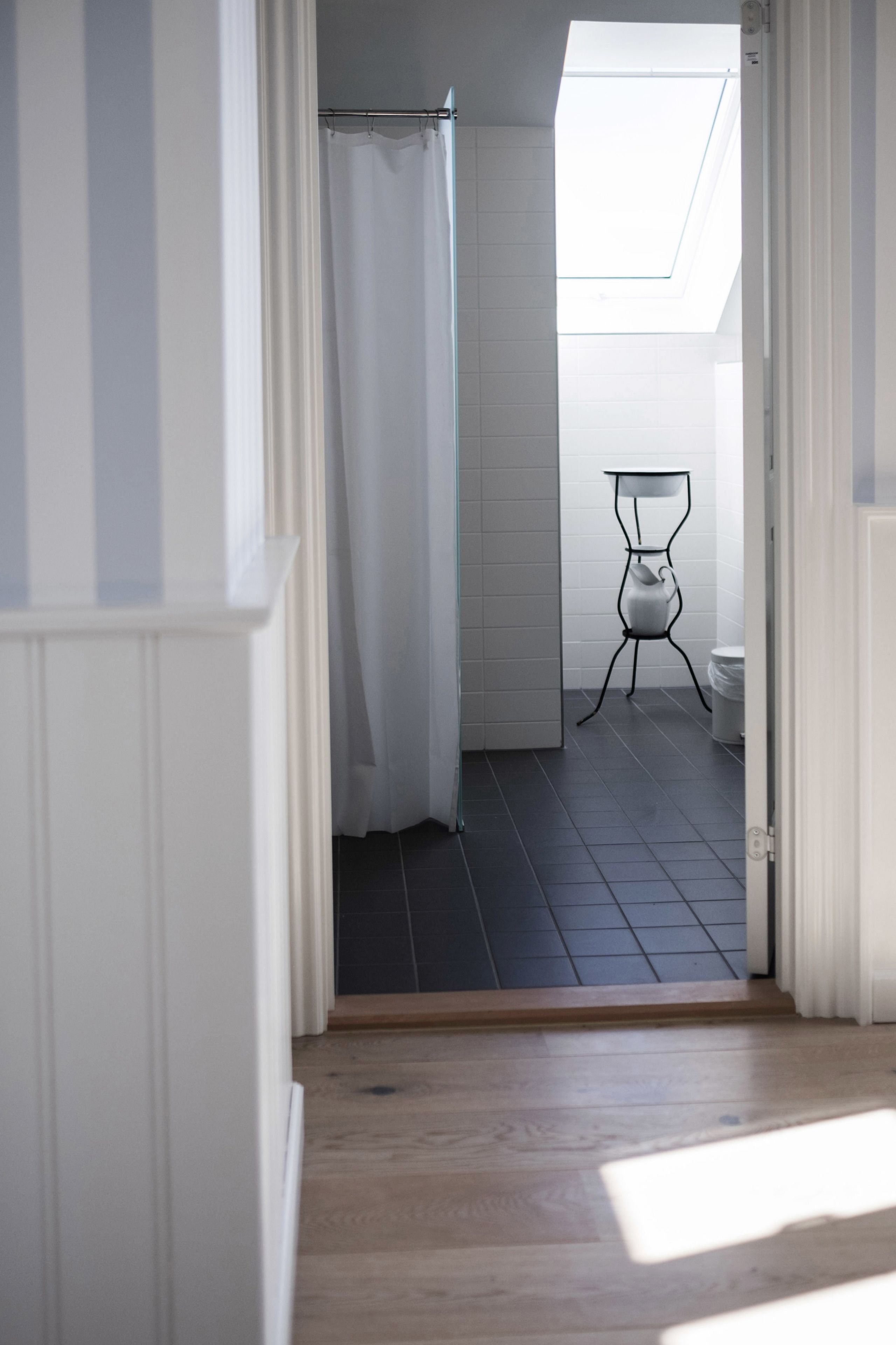 Ein Badezimmer mit Oberlicht, Duschvorhang, Toilette und einem Stuhl.