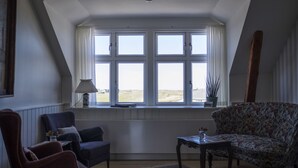 Ein Zimmer mit einem großen Fenster, einem Sofa, einem Sessel und einem kleinen Tisch.