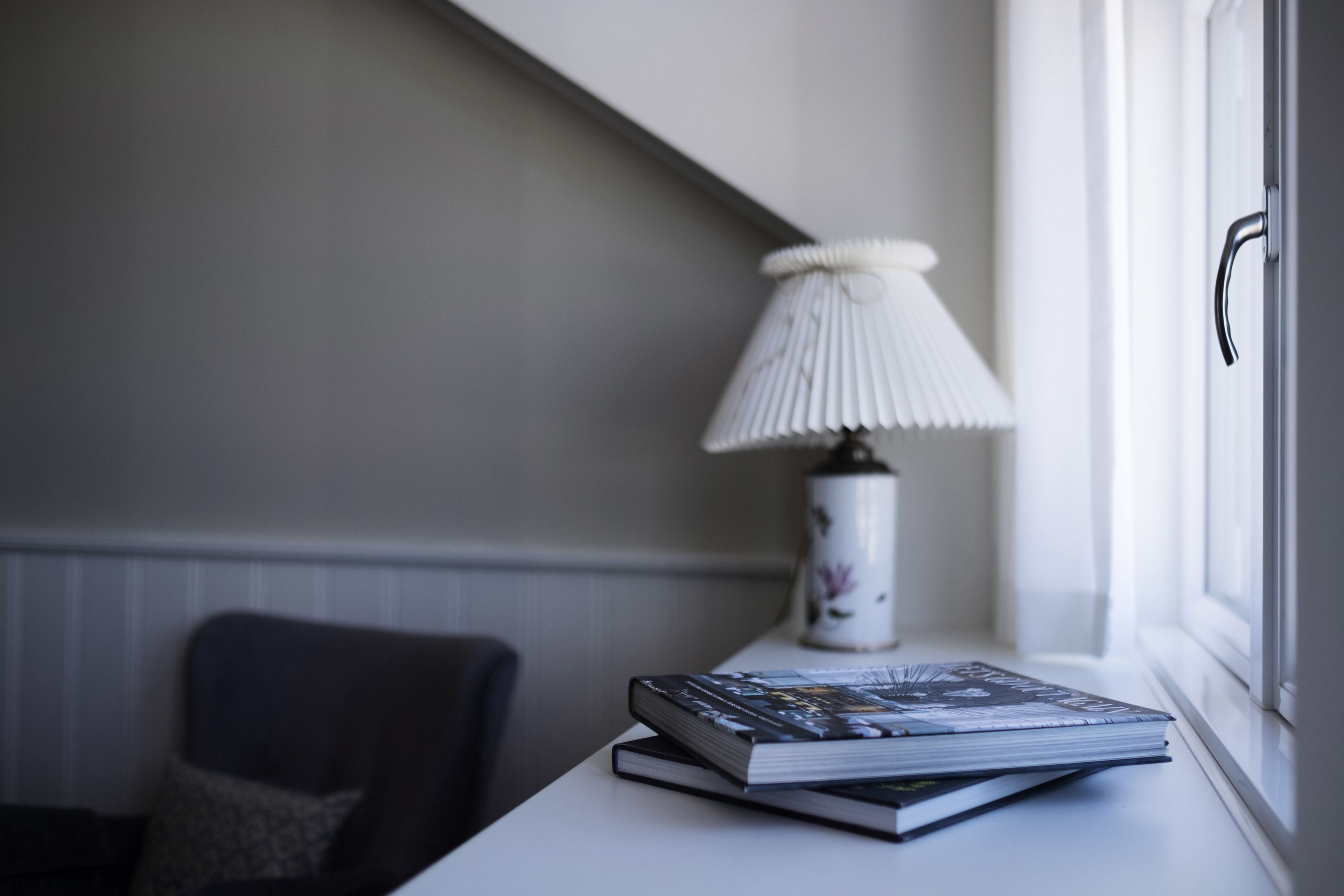 A room with a window, a lamp, and a chair.