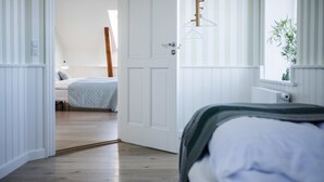 Ein Zimmer mit einem Bett, einer Tür zu einem anderen Raum, einem Heizkörper und einem Fenster mit einer Pflanze.