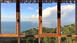 A view through a window with a wooden frame and a decorative valance, overlooking a coastal landscape with buildings and greenery. - Kafdagi Konak Hotel (Derepazari)