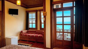 A room with a wooden bench, a television, and a large window with a view of the sea. - Kafdagi Konak Hotel (Derepazari)
