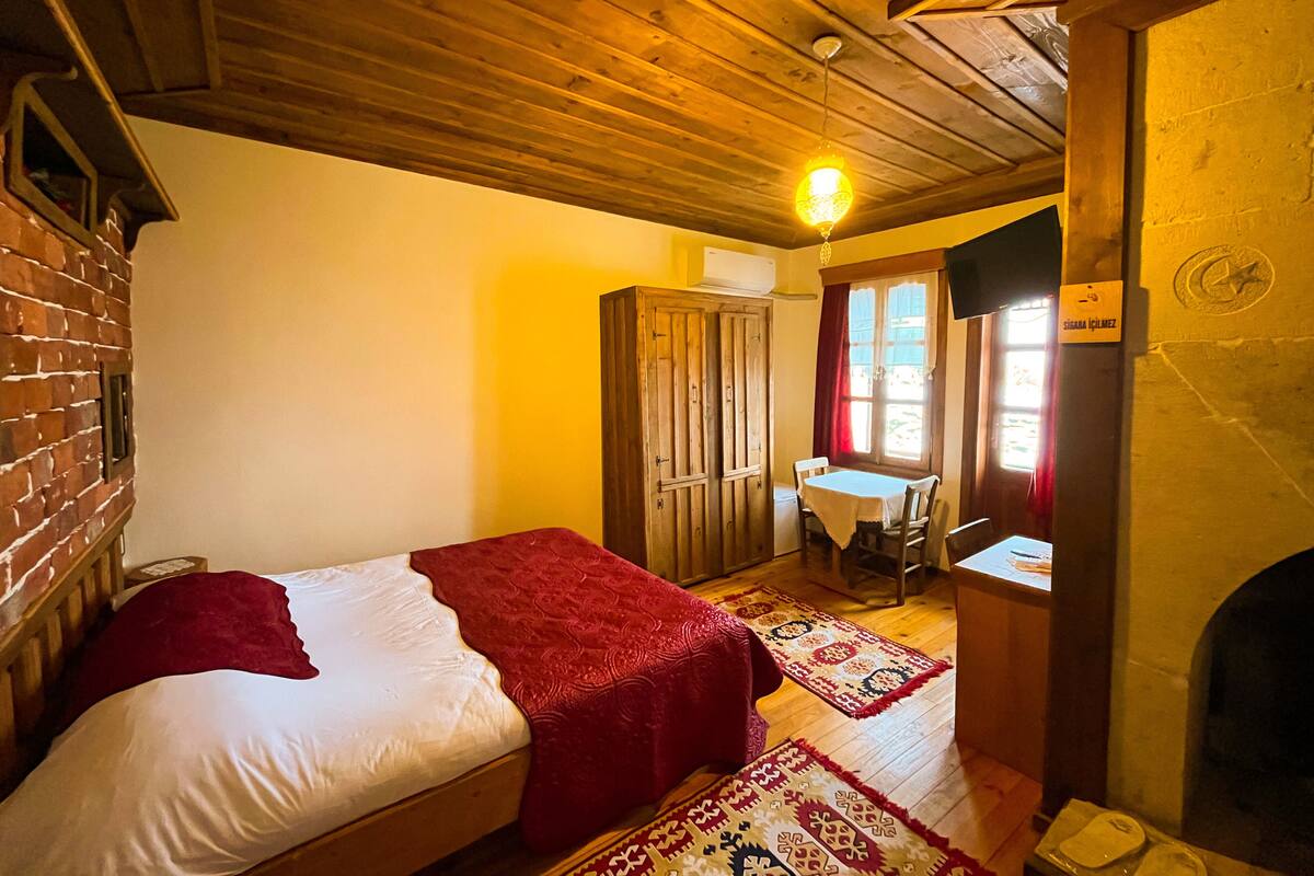 A room with a bed, a table, and a fireplace.
