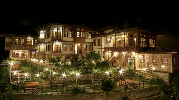 A multi-story hotel with outdoor seating and a stone retaining wall. - Kafdagi Konak Hotel (Derepazari)