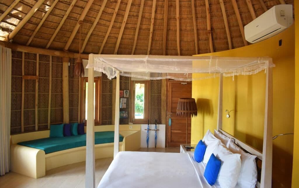 A room with a bed, a daybed, and a mosquito net.