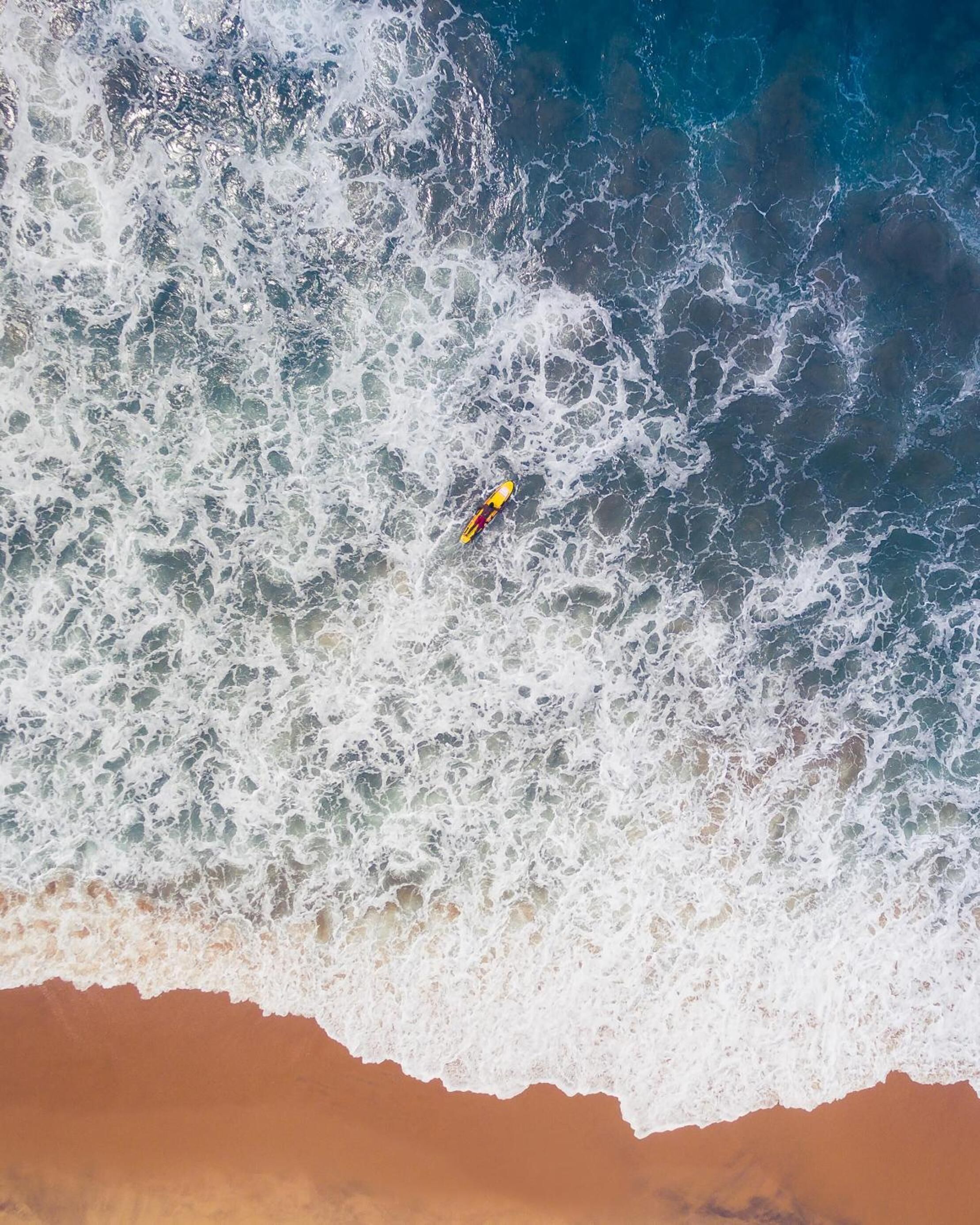 Una persona su una tavola da surf gialla e rossa nell'oceano.
