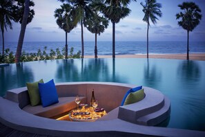 A poolside seating area with a view of the beach and ocean.