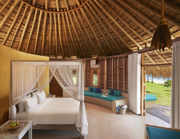 A room with a thatched roof, a bed with a canopy, a sofa, and a view of the outdoors. - Jetwing Surf & Safari, A Luxury Reserve (Pottuvil)