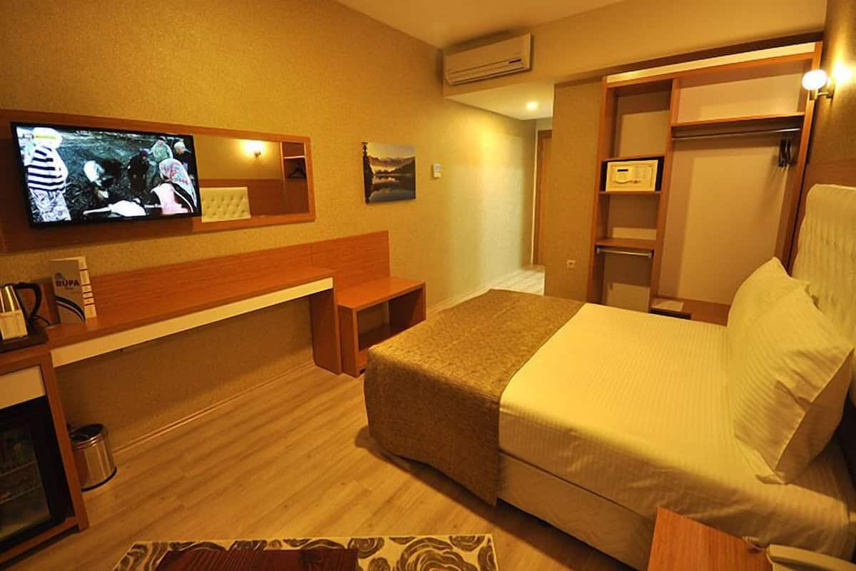 A hotel room with a bed, a desk, a television, and a wardrobe.