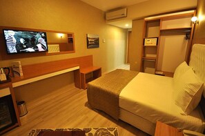 Une chambre d’hôtel équipée d’un lit, d’un bureau, d’une télévision et d’une armoire.