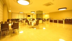 A spacious dining area with multiple tables and chairs, a kitchen area, and a ceiling with circular lights. - Bupa Hotel (Kayseri)