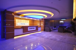 A reception area with a modern design, featuring a reception desk labeled "RECEPTION" and a digital clock displaying the time.