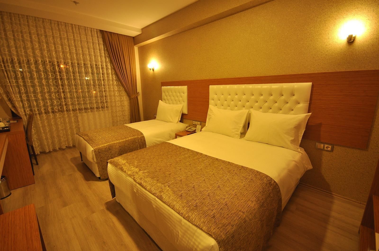 Une chambre d’hôtel avec deux lits, une tête de lit en bois, un bureau et une chaise.