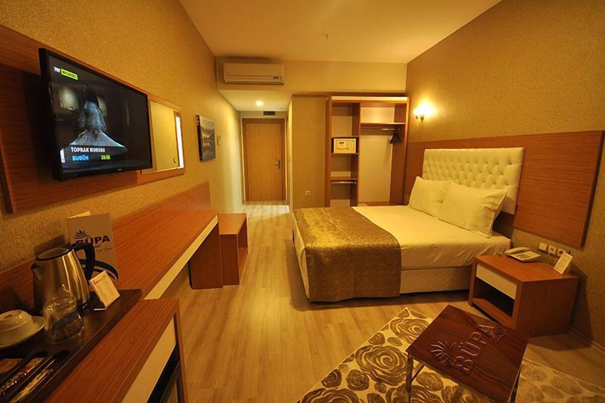 A hotel room with a television, a bed, a desk, and a small table.