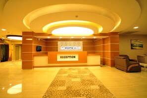 A hotel reception area with a reception desk, a reception sign, and a carpeted floor. - Bupa Hotel (Kayseri)