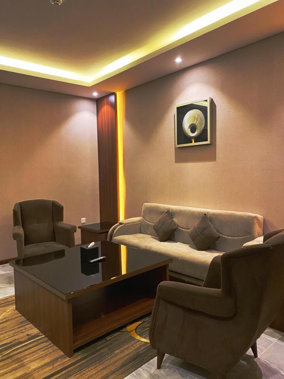 A modern living room with a sofa, armchairs, a coffee table, and a wall-mounted artwork.