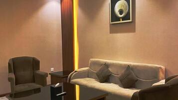 A modern living room with a sofa, armchairs, a coffee table, and a wall-mounted artwork.