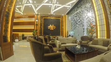 Un lobby moderno con diseño de techo en forma de estrella, asientos cómodos y una pared decorativa con un logotipo.