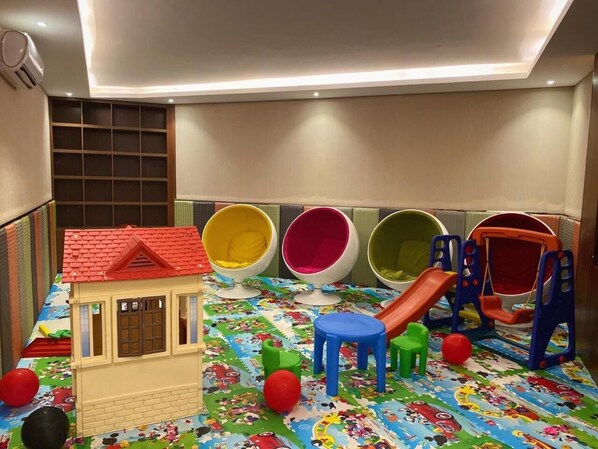 Uma área de recreação com uma casinha, escorregas e assentos coloridos.