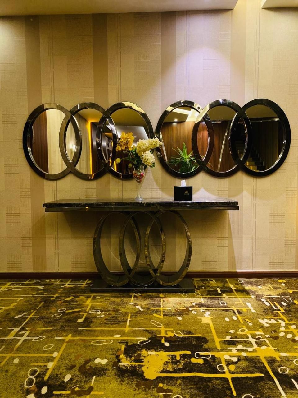 A wall with multiple round mirrors and a vase with flowers.