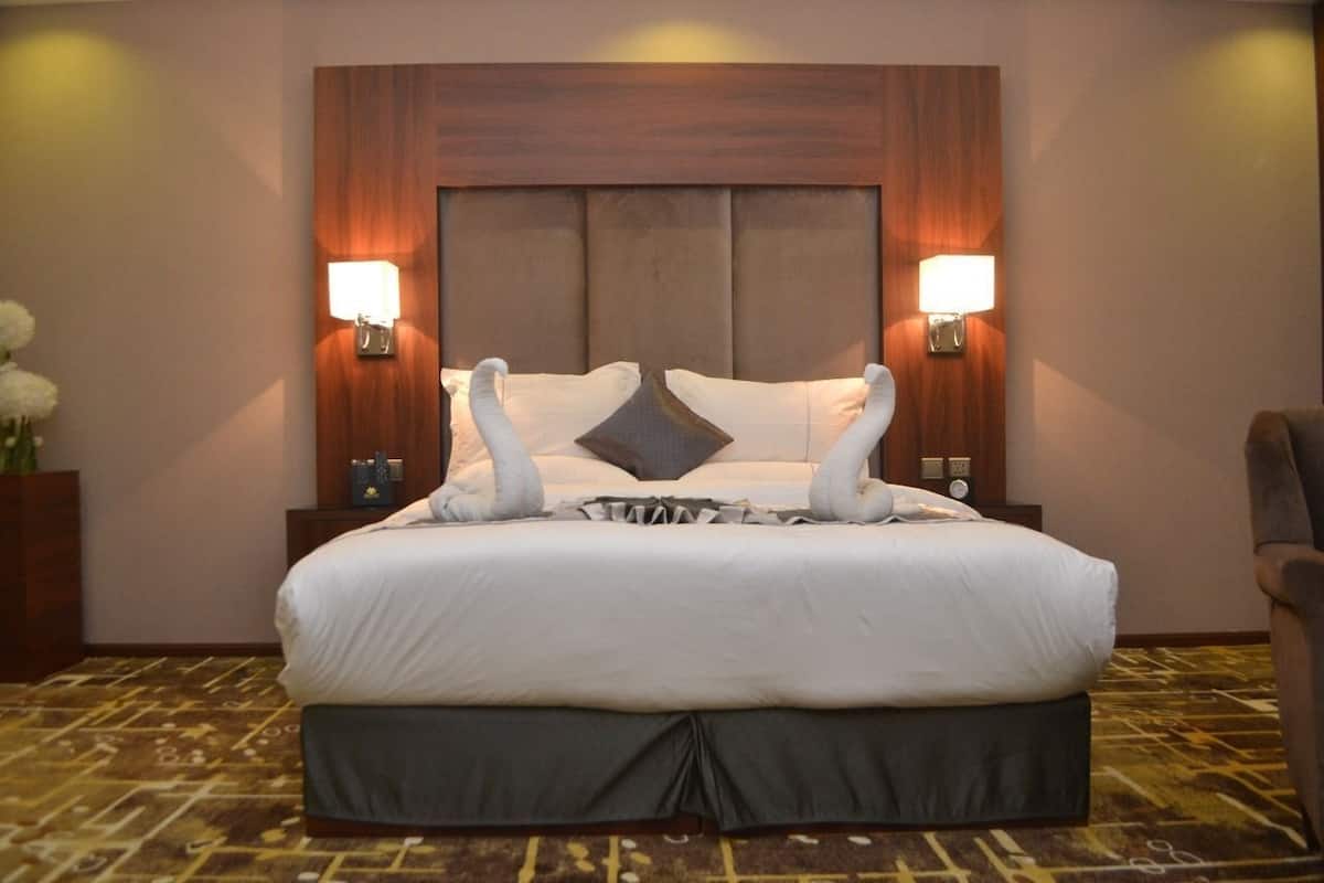 A hotel room with a large bed, two wall-mounted lamps, and a decorative pillow.